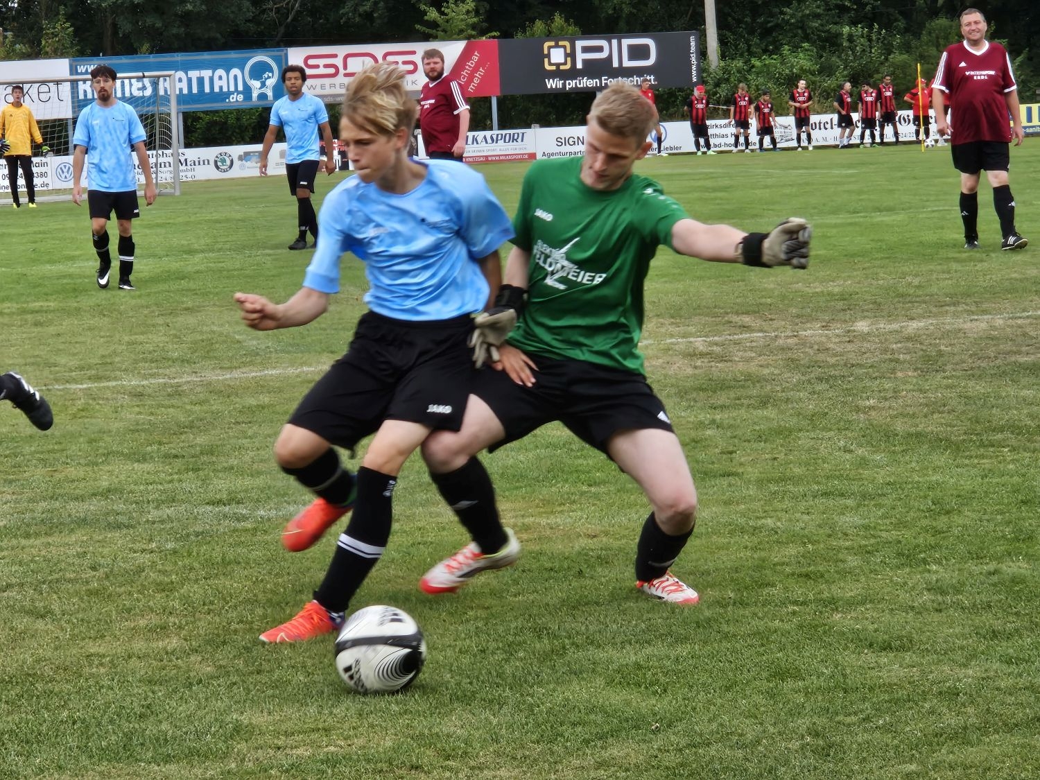 Ein Spieler mit blauem Dress und ein Spieler mit einem grünen Dress im Zweikampf um den Ball